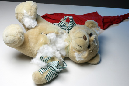 Gewalt an Kindern Zerschnittener Teddybär mit rotem Tuch im Hintergrund